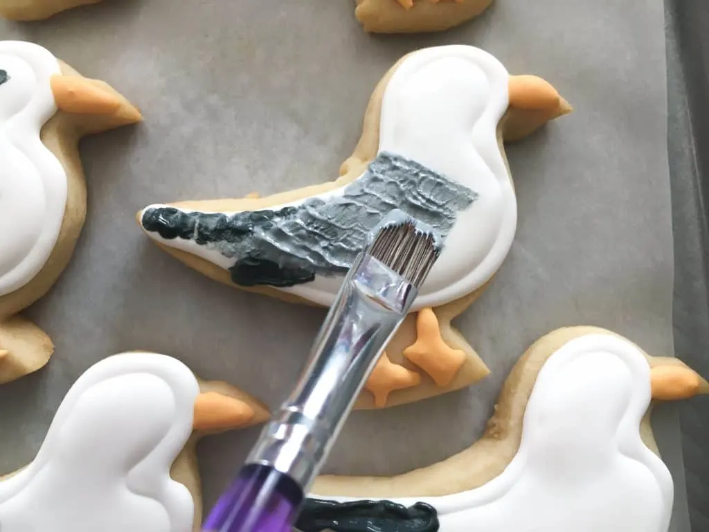 how to paint on the feathers on a seagull cookie using a paintbrush