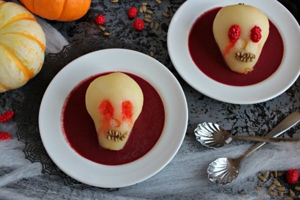 Halloween dessert with pears that look like skulls in red fruit puree