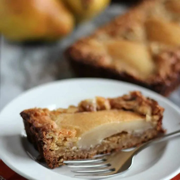 Gluten free pear and walnut tart slice on a white plate