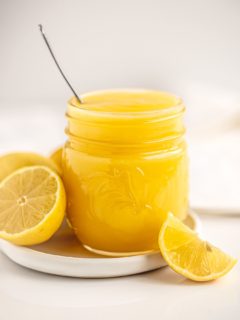 jar filled with bright yellow microwave lemon curd with fresh lemons