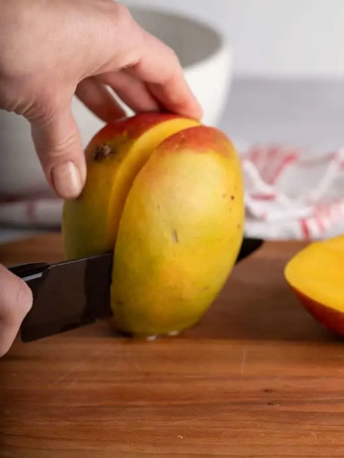 person cutting a mango with a knife