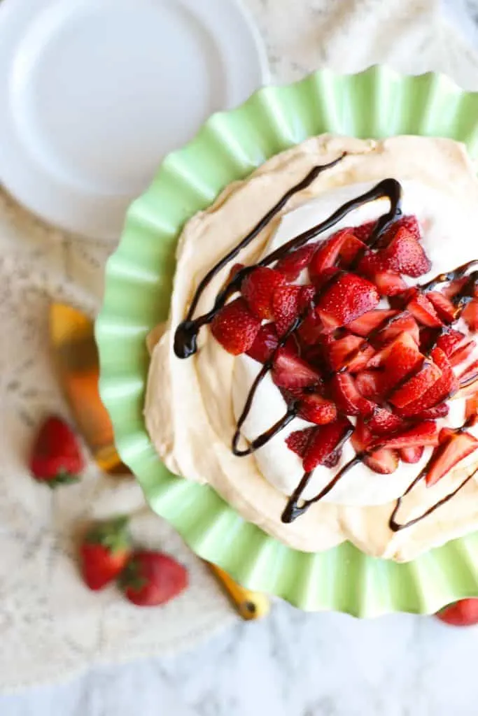 Pavlova with strawberries and balsamic glaze on green plate