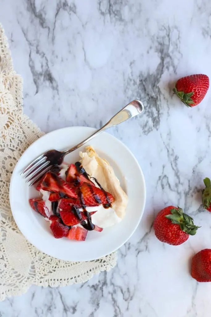slice of pavlova with strawberries on white plate with fork