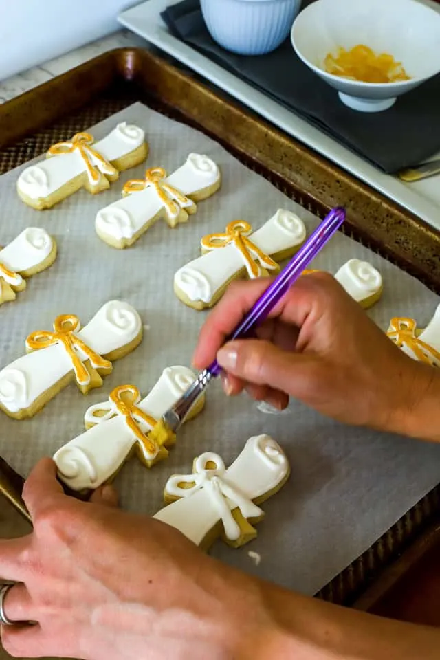 paintbrush adding gold lustre dust to sugar cookies with a paint brush
