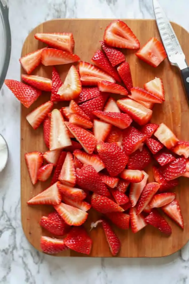 sliced strawberries on a wooden cutting board