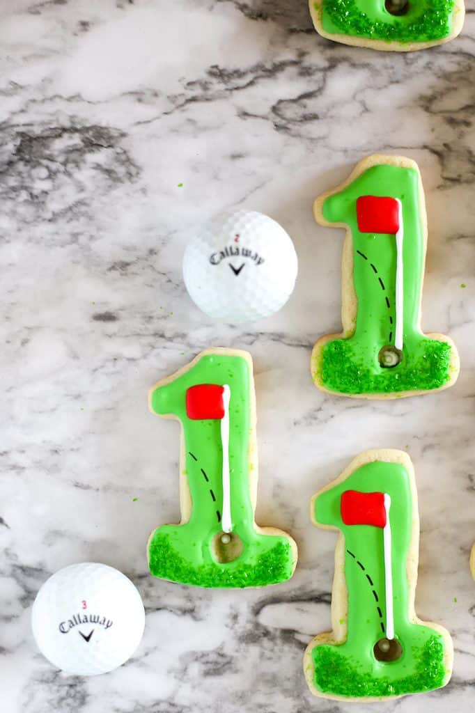 Hole in one cut out cookies with golf ball on a marble board