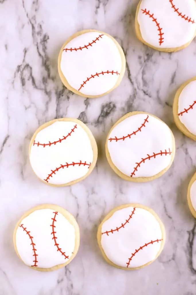 Baseball cookies in the shape of a ball decorated with red lines for the baseball stitches