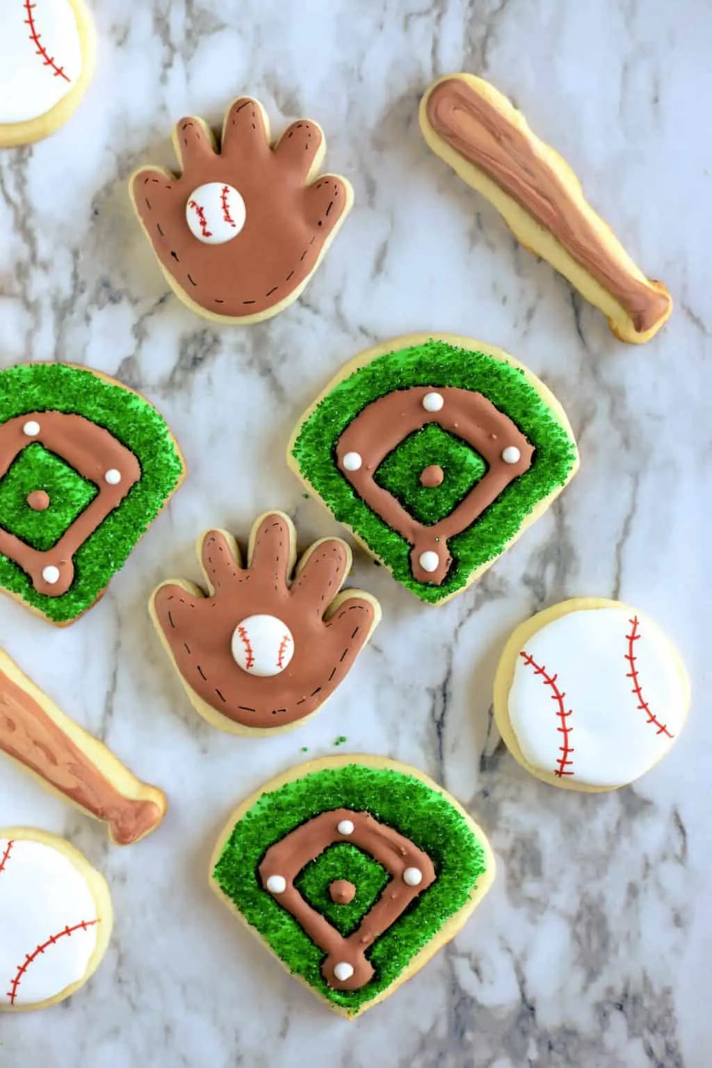 Assortment of baseball cookies including gloves, balls, bats and baseball diamonds