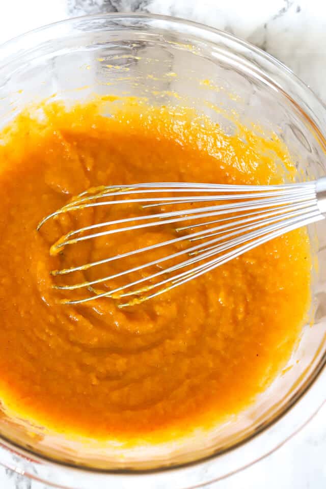 whisk in a glass bowl with pumpkin mixture