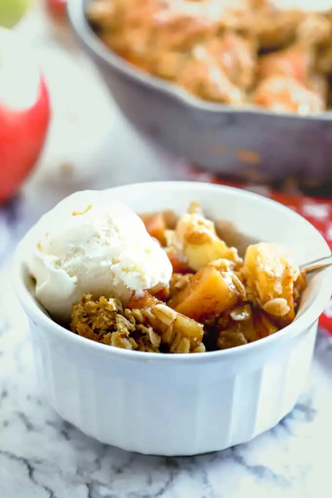 Serving of gluten free Easy Apple Crisp in a white bowl on a marble countertop
