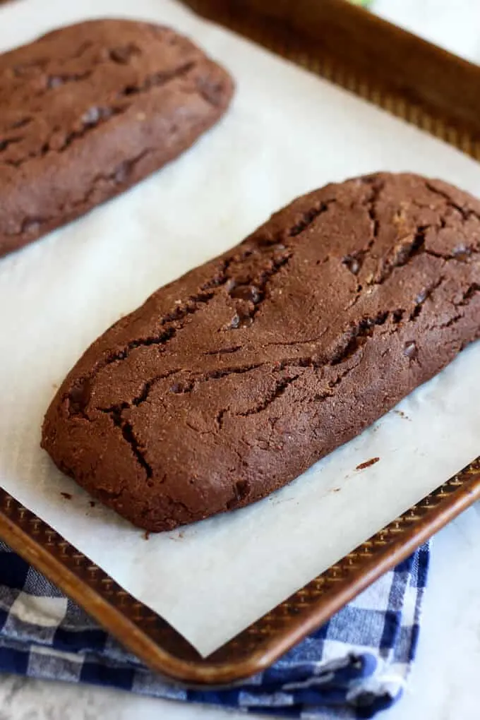 Baked vegan chocolate biscotti resting on baking pan before cutting