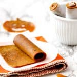 Pumpkin fruit leather roll on parchment with an orange napkin and pumpkin shape in background