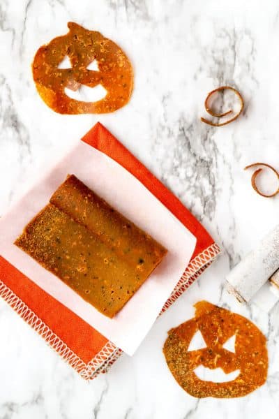 Rolled up pumpkin fruit leather on parchment paper and orange napkin