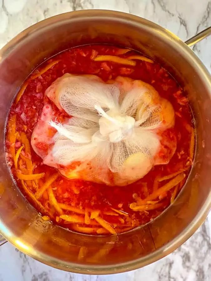 Cheesecloth filled with orange peels in the mixture for making marmalade