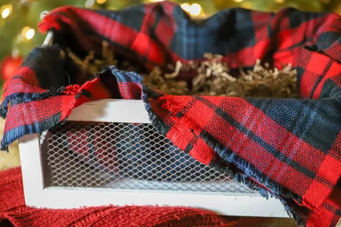 plaid blanket in the bottom of a white crate for gift basket