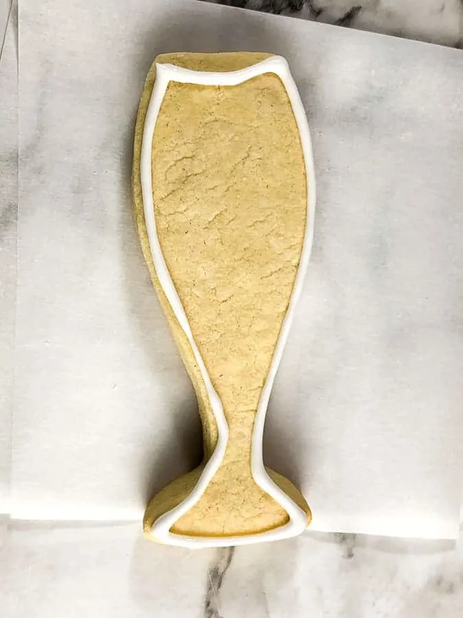 Champagne glass shaped cookie with white outline of icing