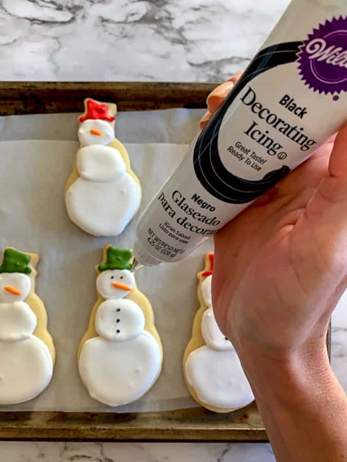 Add black icing to make eyes and buttons on snowman cut out cookies