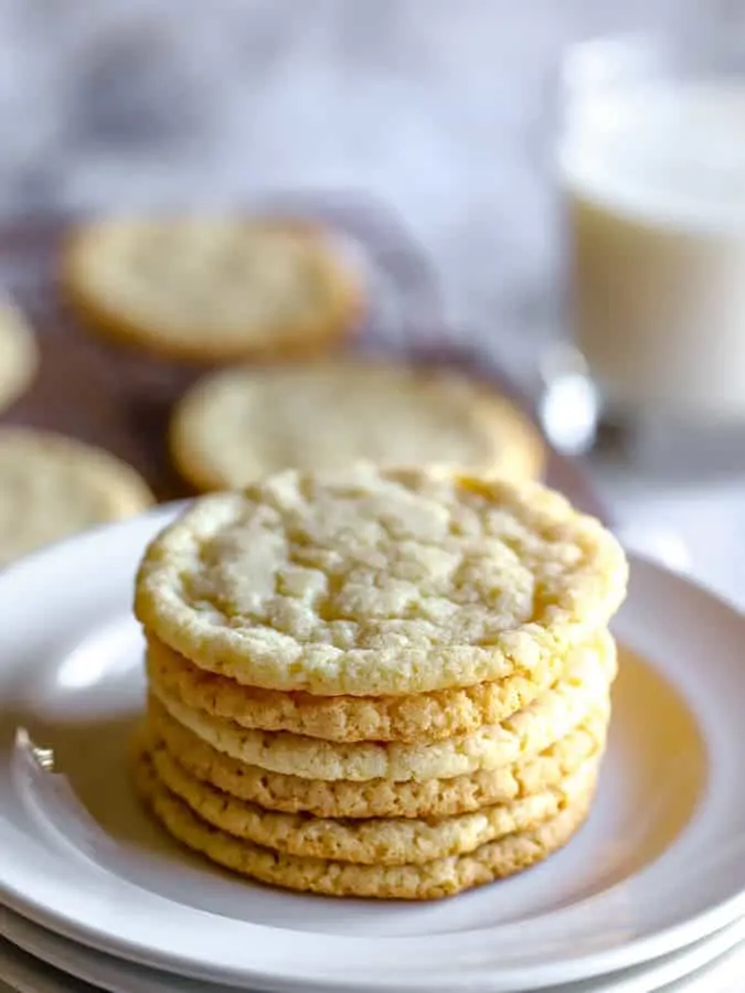 Stack of almond flour sugar cookies on a white plate with milk in background