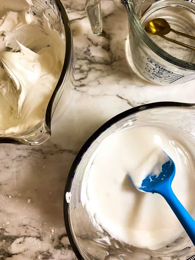 White royal icing in a bowl with a blue spatula