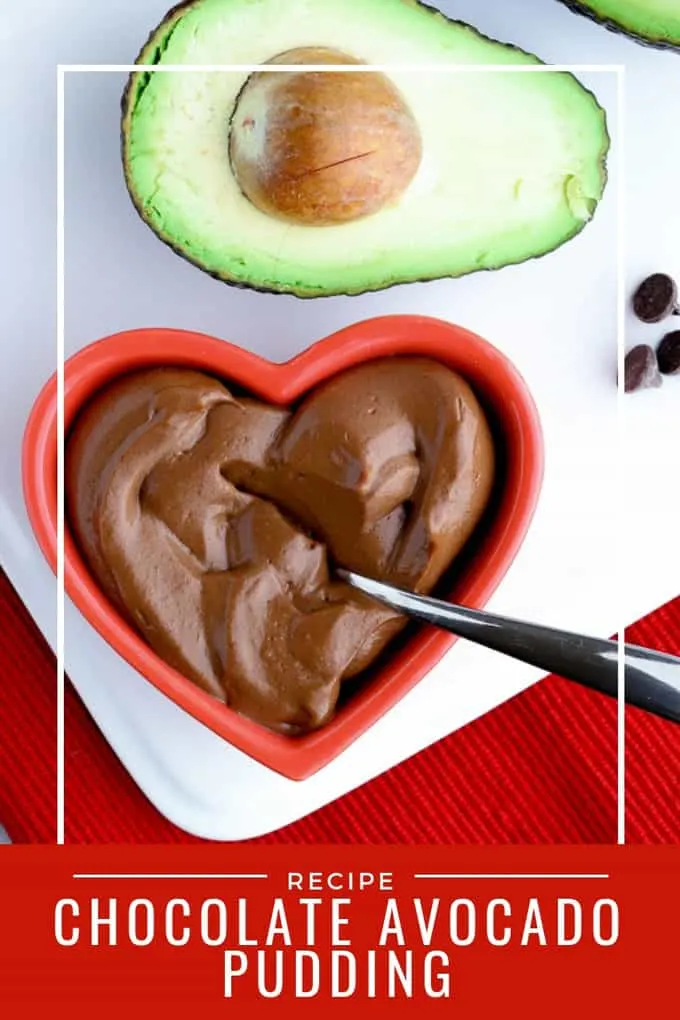 Pinterest image for healthy chocolate avocado pudding in a red heart shaped dish with avocado on white palte