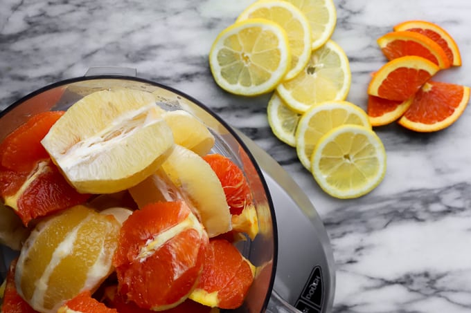 Slices lemons and cara cara oranges in the food processor for making marmalade