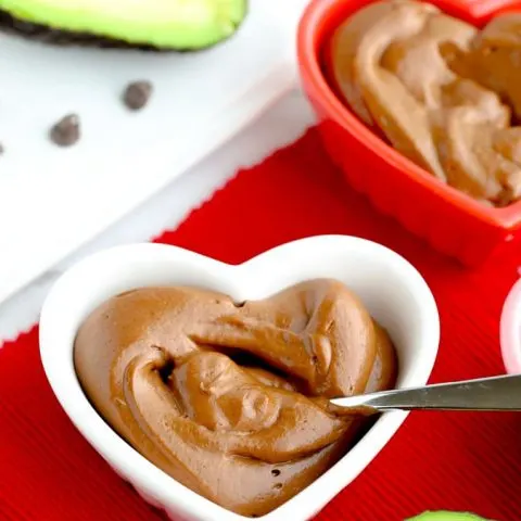 Healthy avocado chocolate pudding in a heart bowl on red napkin