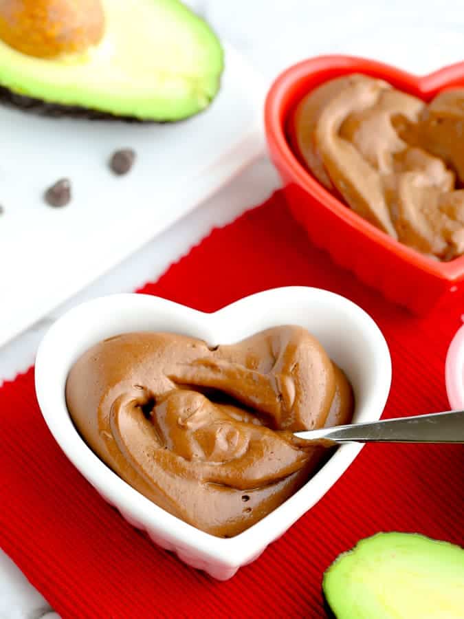 Healthy avocado chocolate pudding in a heart bowl on red napkin