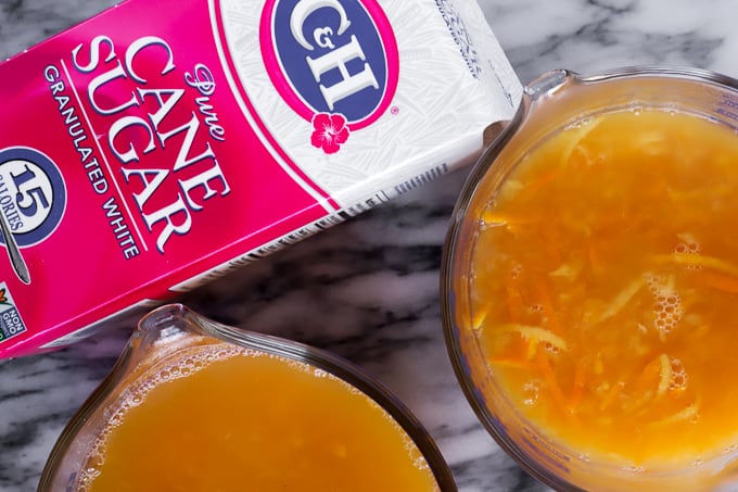 Two glass measuring cups of orange marmalade fruit mixture and sugar