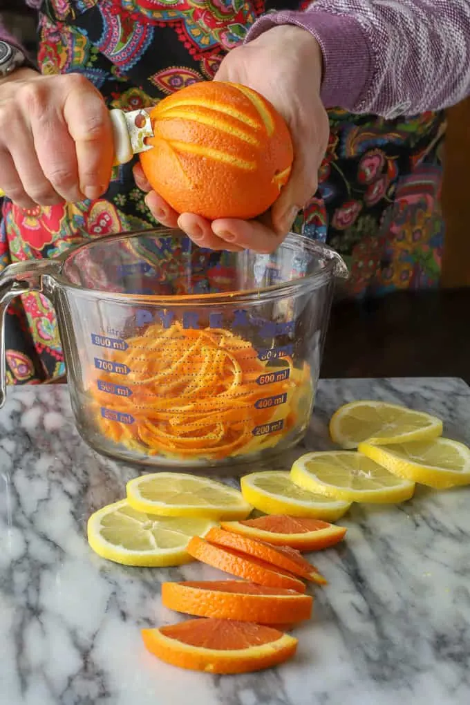 Hand using a citrus zester to peel zest of orange