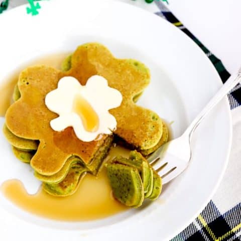 Shamrock shaped spinach pancakes on a plate with butter and syrup