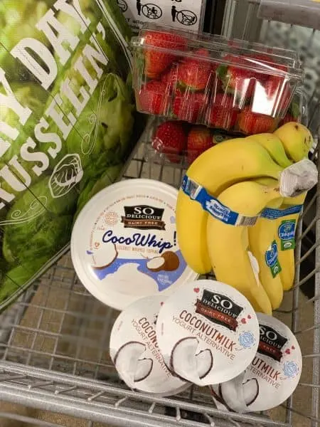 Grocery cart with Sprouts farmers market items bananas strawberries and yogurts