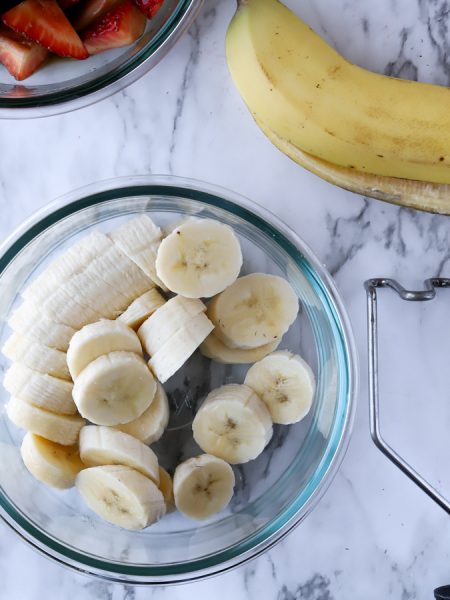 sliced bananas in a glass bowl on marble countertop