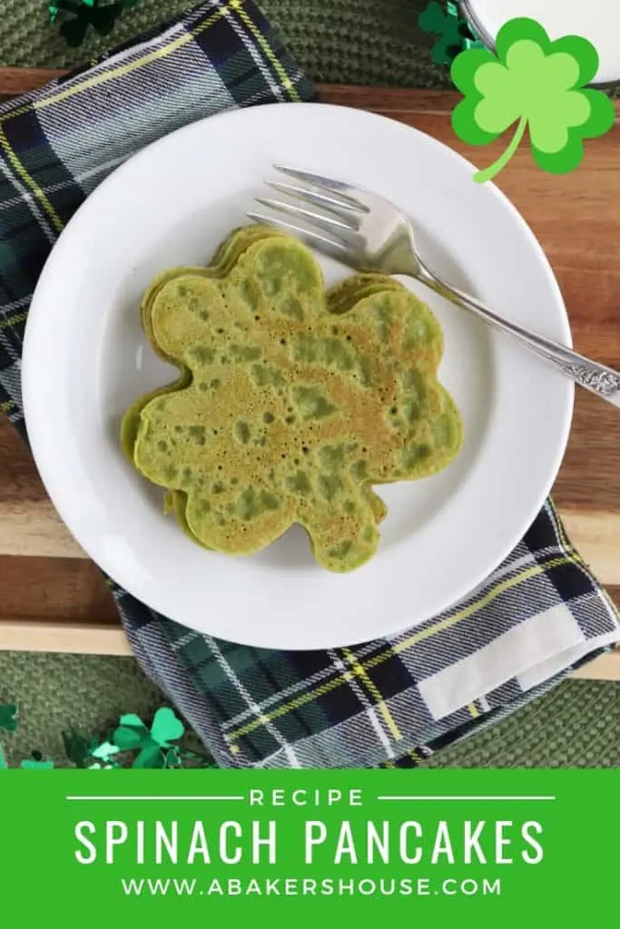 Green pancakes shaped like shamrocks on white plate and plaid napkin
