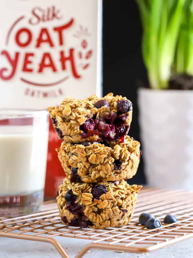 Stack of three baked oatmeal cups with oat Yeah in background