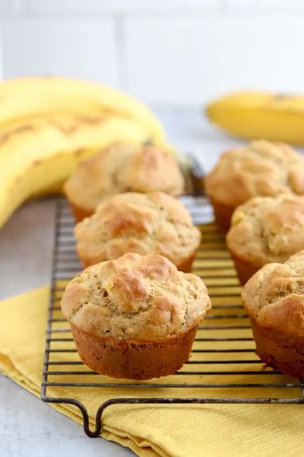 Banana muffins on baking rack with bananas in background