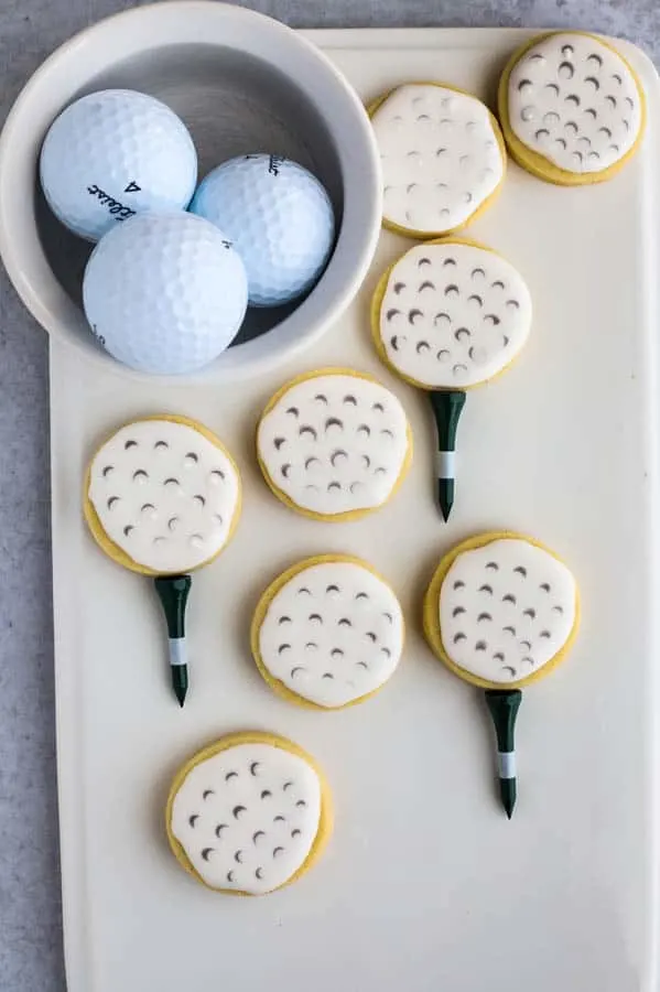 golf ball cookies finished sugar cookies on a white plate with bowl of golf balls