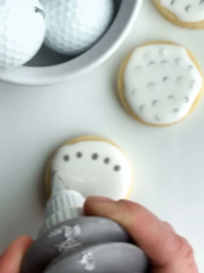 Add gray circles to the wet white icing on golf cookies