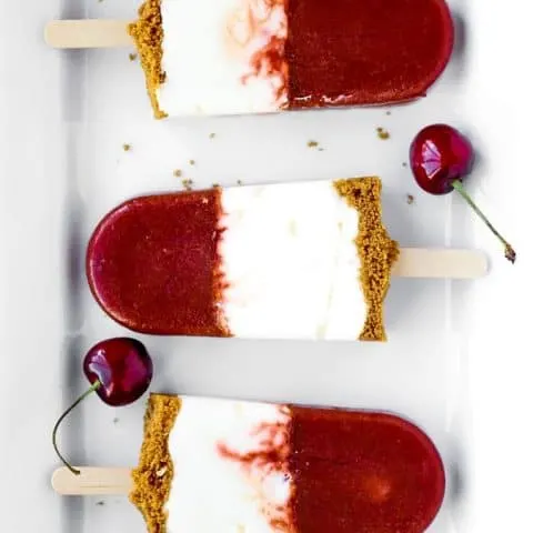 Cherry Cheesecake Popsicles with three layers on a white platter