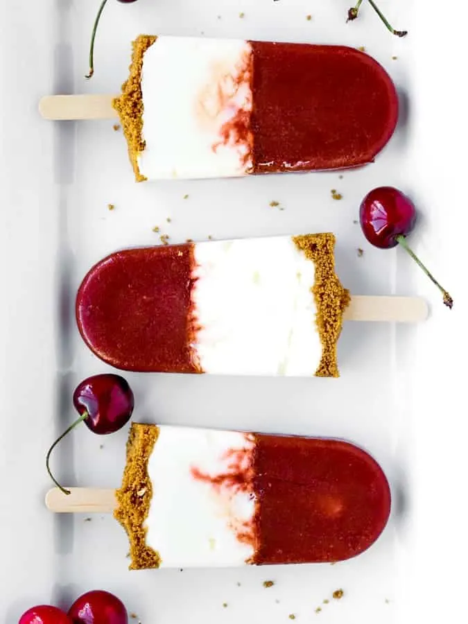 Cherry Cheesecake Popsicles with three layers on a white platter