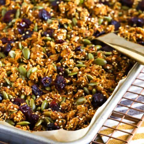 A baking tray filled with pumpkin granola and a serving spoon