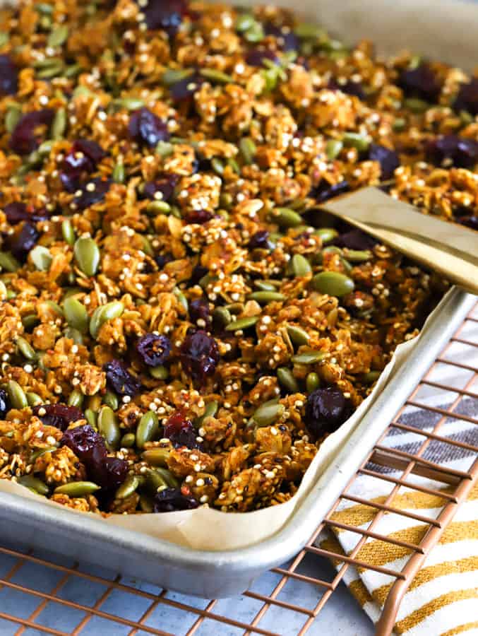 A baking tray filled with pumpkin granola and a serving spoon