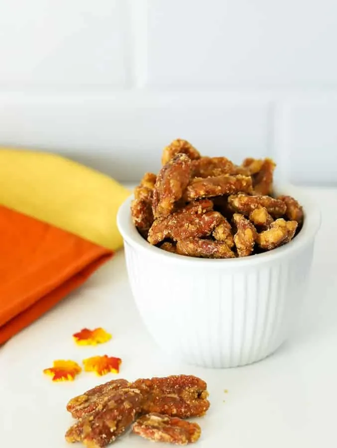 Maple candied pecans in white bowl with orange and yellow napkins