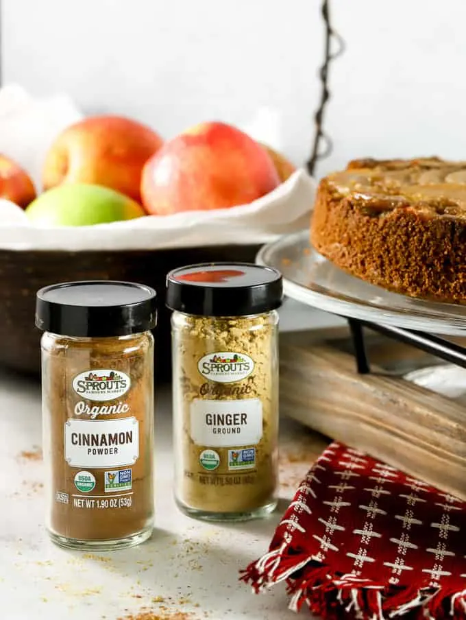 Sprouts farmers market spices cinnamon and ginger with apple basket in background and apple cake
