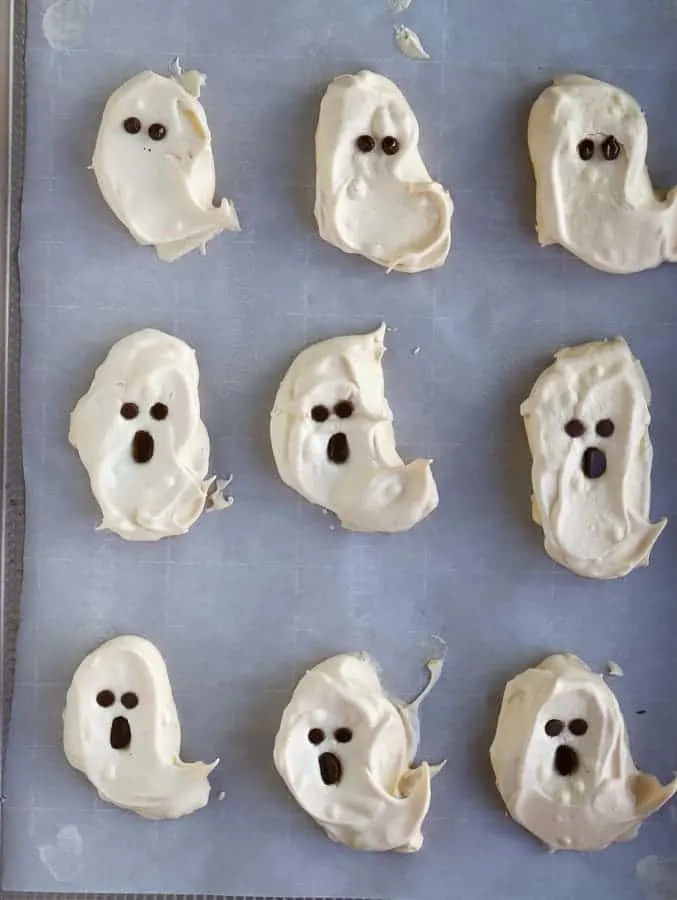 ghost meringues with chocolate faces with two eyes and round mouth