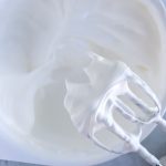 egg whites in white bowl whipped to stiff peaks