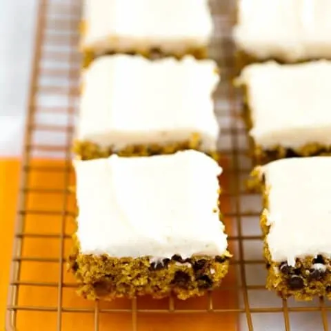 Gluten free pumpkin bars with cream cheese frosting on gold wire baking rack