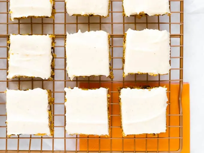 Cream cheese frosted pumpkin bars on wire baking rack