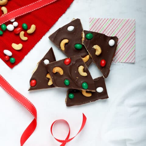 Overhead photo of pieces of cashew bark on white surface with red ribbon