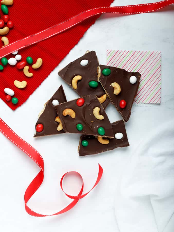 Overhead photo of pieces of cashew bark on white surface with red ribbon