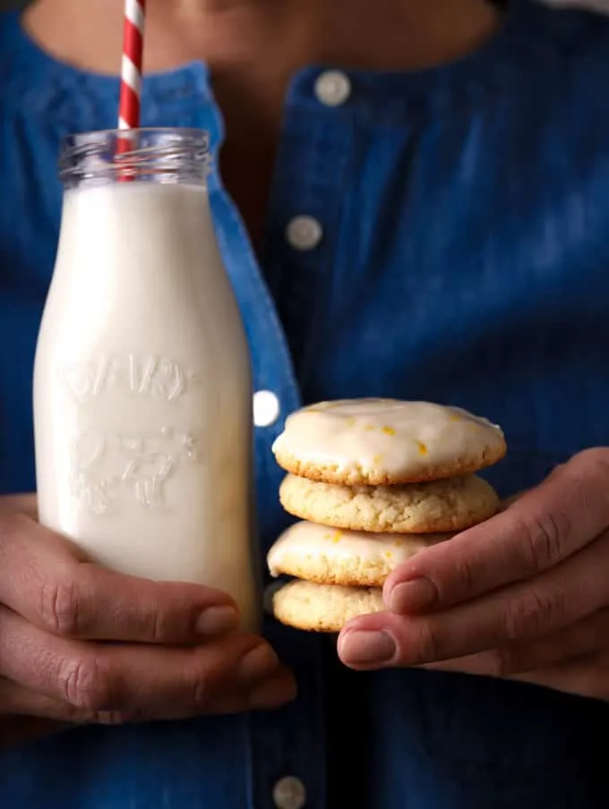 person holding a glass of milk and stack of cookies